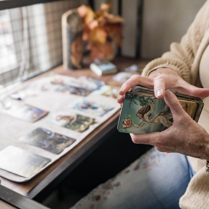 An elderly person holding a decorated jar near a photo album.