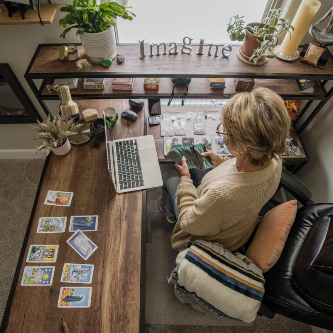 Person working on a laptop at a cozy wooden desk with photos and plants.