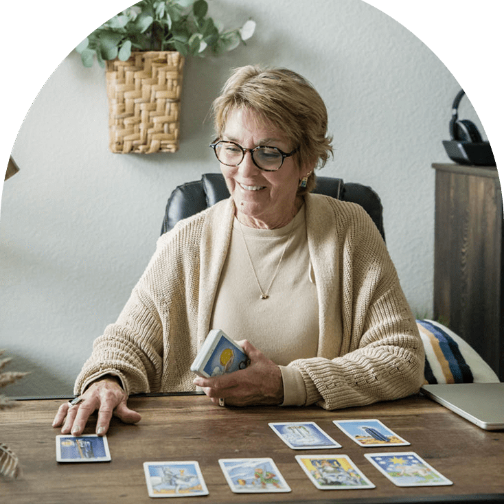 A woman reading tarot cards at a table.