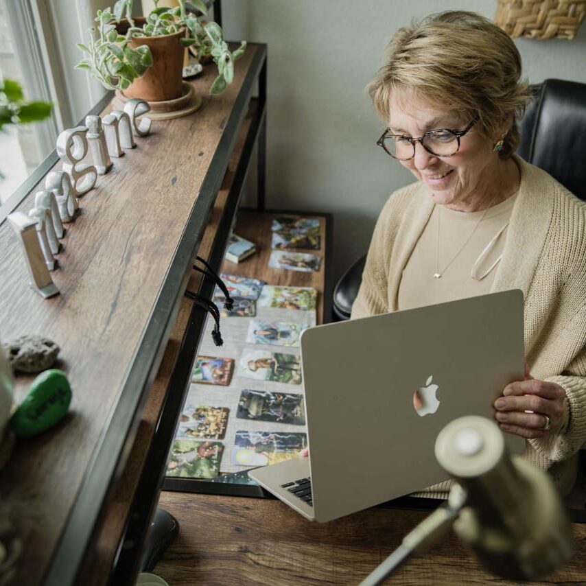 A woman reviewing old photos while holding a laptop.