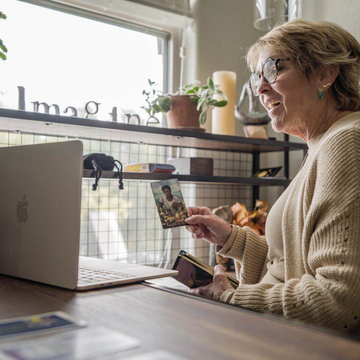 Woman working on laptop while holding smartphone in cozy cafe.