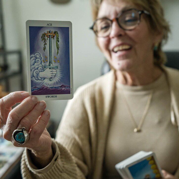 Woman smiling while holding a tarot card.