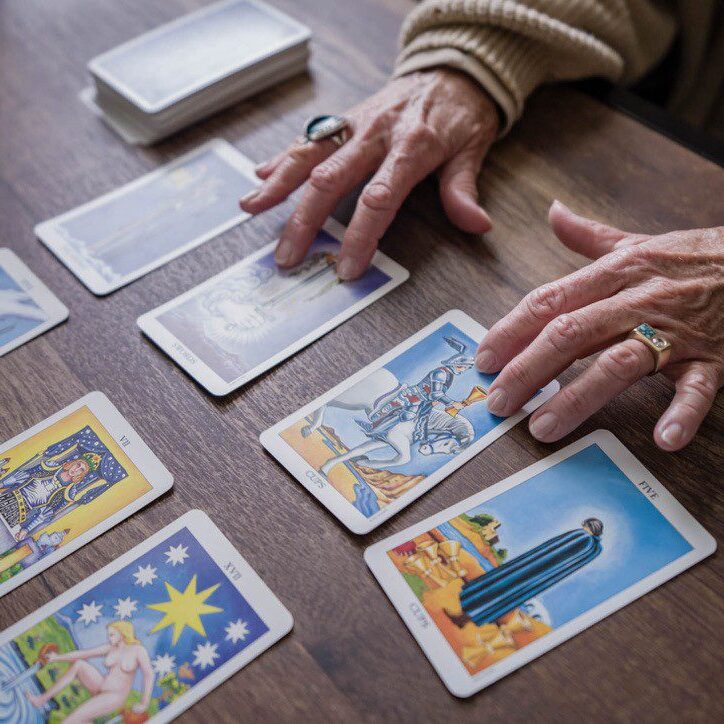 Hands arranging tarot cards on a table, exploring future insights.